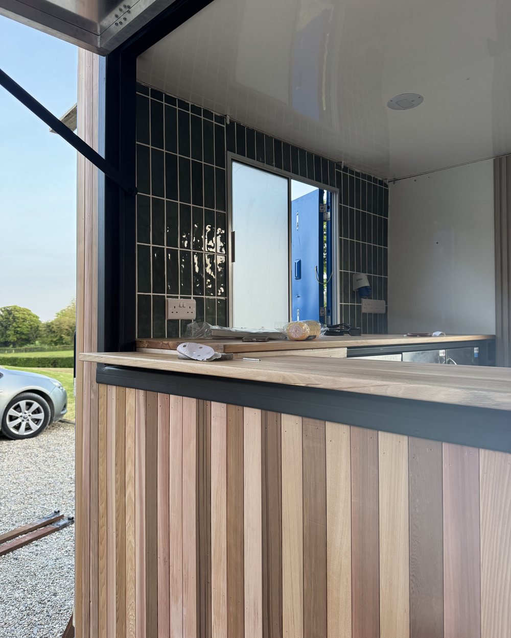 Finished unit: vertical timber cladding, solid timber counter and green tiled interior