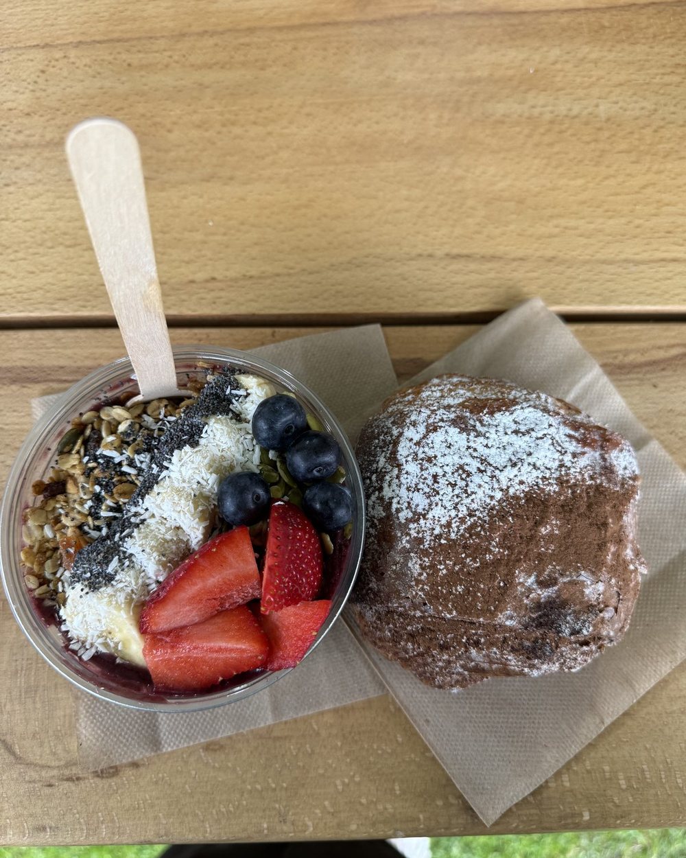 An açaí bowl with strawberries, blueberries, banana and coconut next to a brownie